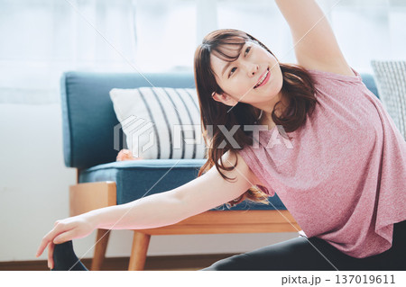 自宅で体をほぐすストレッチをする30代女性の健康習慣 自宅で体をほぐすストレッチをする30代女性の健康習慣 137019611