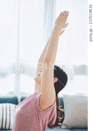 自宅のリビングでヨガポーズをする30代女性のフィットネスライフ 137019616