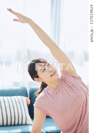 自宅で体をほぐすストレッチをする30代女性の健康習慣 137019624