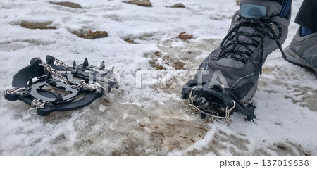 Crampons for shoes for walking on icy surfaces and winter mountain trips. Essential equipment for safe hiking on icy trails. High quality photo Crampons for shoes for walking on icy surfaces and winter mountain trips. Essential equipment for safe hiking on icy trails. High quality photo 137019838