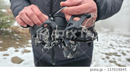 Crampons for shoes for walking on icy surfaces and winter mountain trips. Essential equipment for safe hiking on icy trails. High quality photo Crampons for shoes for walking on icy surfaces and winter mountain trips. Essential equipment for safe hiking on icy trails. High quality photo 137019845