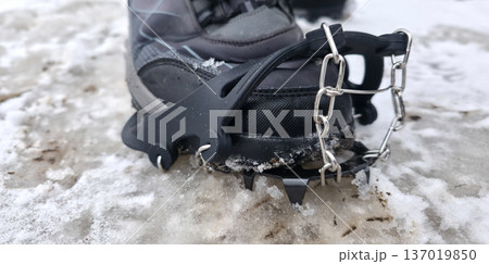 Crampons for shoes for walking on icy surfaces and winter mountain trips. Essential equipment for safe hiking on icy trails. High quality photo Crampons for shoes for walking on icy surfaces and winter mountain trips. Essential equipment for safe hiking on icy trails. High quality photo 137019850