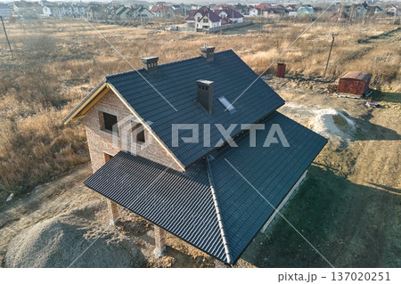 Aerial view of house roof top covered with ceramic shingles. Tiled covering of building under construction 137020251