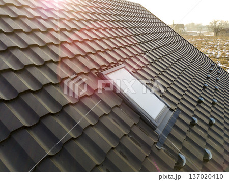 Close-up of new attic plastic window installed in shingled house roof. Professionally done building and construction work, roofing and installation concept. 137020410