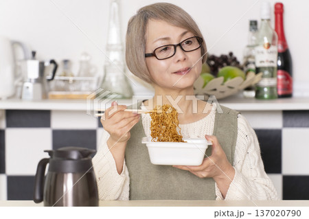 キッチンでカップ麺にお湯を入れるシニア女性 キッチンでカップ麺にお湯を入れるシニア女性 137020790