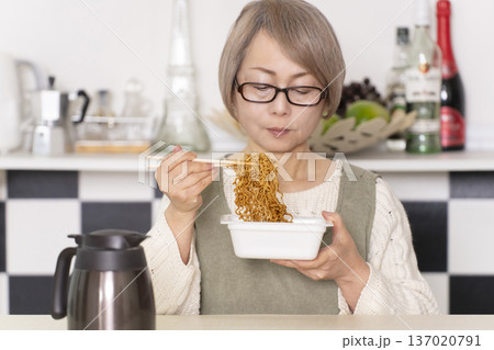 キッチンでカップ麺にお湯を入れるシニア女性 キッチンでカップ麺にお湯を入れるシニア女性 137020791