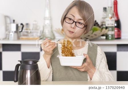 キッチンでカップ麺にお湯を入れるシニア女性 キッチンでカップ麺にお湯を入れるシニア女性 137020940