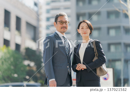 オフィス街に立つスーツの男女 137021582