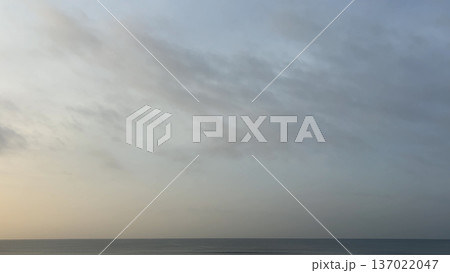 淡い朝焼けの空と水平線が広がる静かな海の風景 137022047