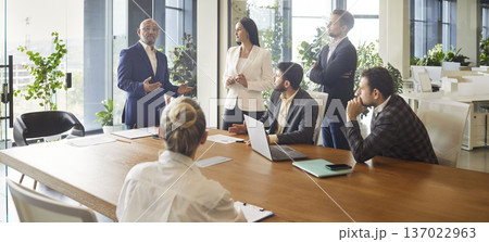 Business leader speaking on office meeting in front of diverse team of employees Business leader speaking on office meeting in front of diverse team of employees 137022963