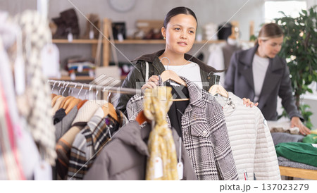 Adult woman chooses outerwear in store Adult woman chooses outerwear in store 137023279