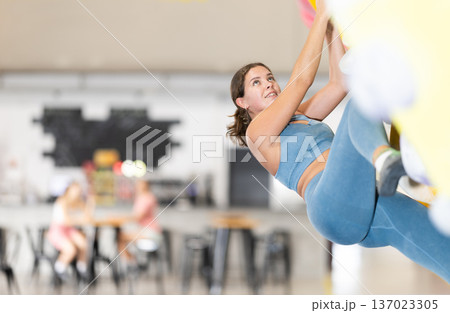 Woman exercising on wall in climbing gym during bouldering training 137023305