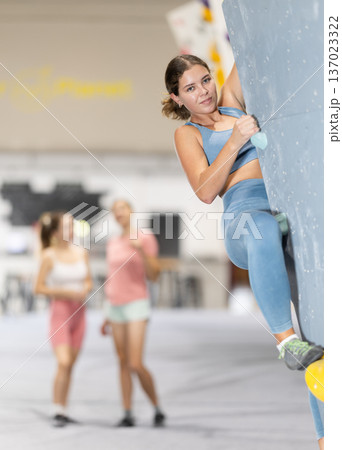 Girl climbs artificial wall bouldering, working out in gym Girl climbs artificial wall bouldering, working out in gym 137023322