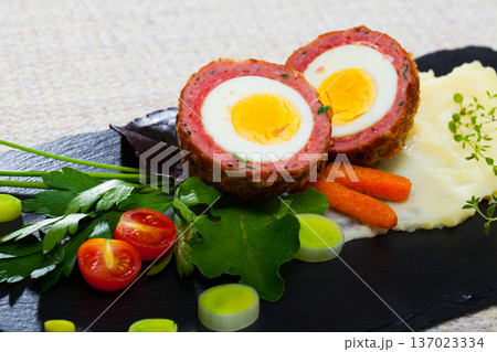 Dishes of traditional Scottish cuisine of scotch egg served with greens and potatoes Dishes of traditional Scottish cuisine of scotch egg served with greens and potatoes 137023334