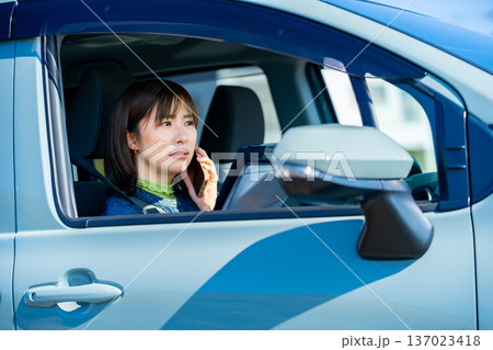 車でスマホで会話をする女性 137023418