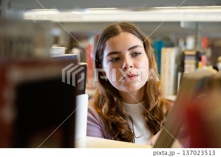 Portrait of woman choosing books at library 137023513