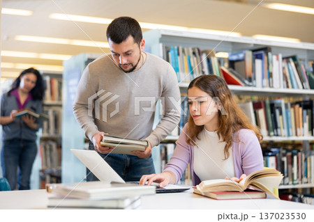 Couple of students spending time together in library Couple of students spending time together in library 137023530