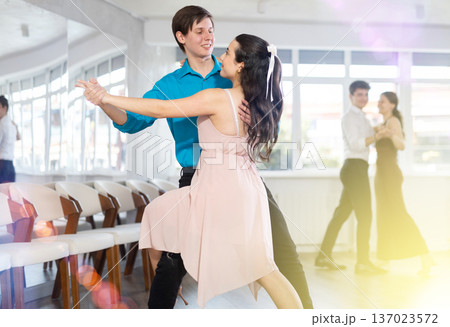Girl and guy in festive clothes dancing slow ballroom dance during group lesson in choreography studio 137023572