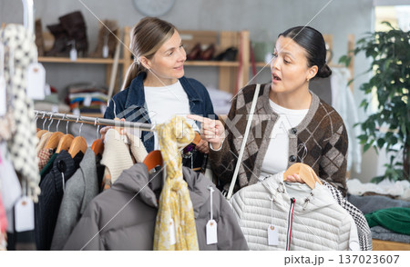 Two women friends browsing goods items and choose elect something autumn outwear 137023607