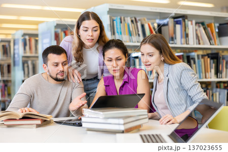 Group of friendly students working on joint research in library Group of friendly students working on joint research in library 137023655