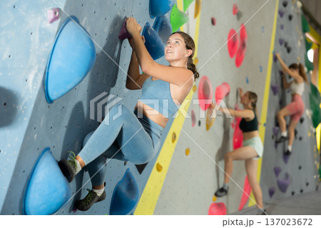 Woman exercising on wall in climbing gym during bouldering training 137023672