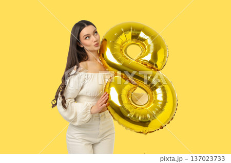 Young woman celebrates day holding golden balloon shaped like 8 137023733