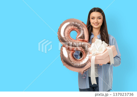 Young woman holds a gift box and balloon for celebration Young woman holds a gift box and balloon for celebration 137023736
