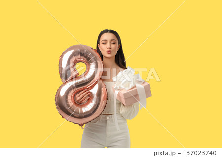 Young woman holds a pink gift and balloon for celebration Young woman holds a pink gift and balloon for celebration 137023740