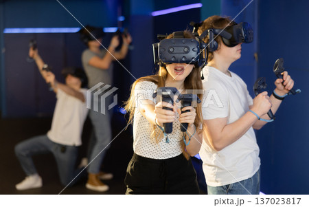 Portrait of woman using virtual reality goggles controlling joysticks standing in dark room 137023817