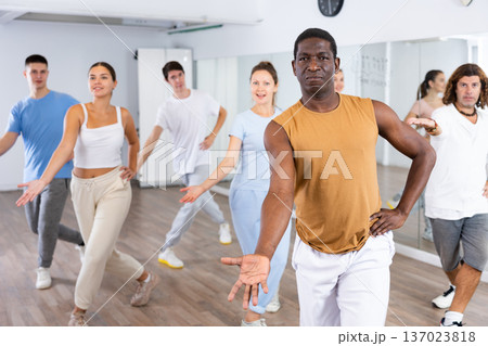Cheerful multiracial people stretching out hand during dancing training in studio Cheerful multiracial people stretching out hand during dancing training in studio 137023818