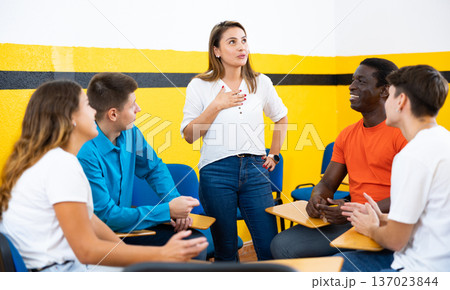 Female student discussing with groupmates sitting in circle in auditorium during classes 137023844