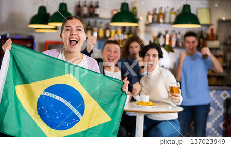 Emotional friends, football fans cheering for favorite Brazil team together while watching match on tv in bar 137023949