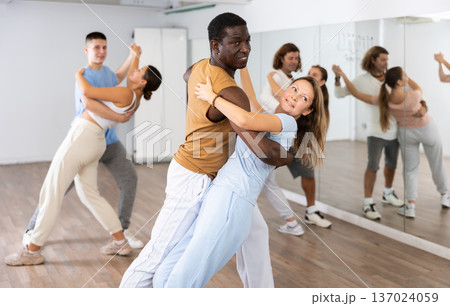 Cheerful diverse young adult people dancing together active expressive dances in pairs in modern class 137024059