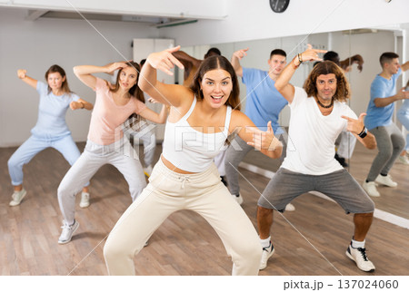 Active positive diverse men and women performing dance elements during lesson in modern fitness gym 137024060