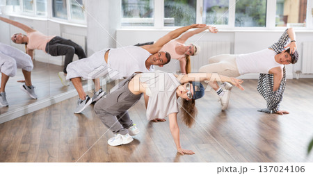 Concetrated guys and girls studying movement of contemporary dance in classroom with his friends Concetrated guys and girls studying movement of contemporary dance in classroom with his friends 137024106