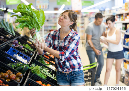 Young woman choosing green chard on showcase in supermarket Young woman choosing green chard on showcase in supermarket 137024166