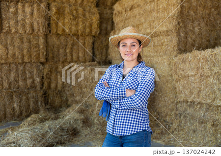 Portrait of a positive woman farmer standing near haystacks Portrait of a positive woman farmer standing near haystacks 137024242