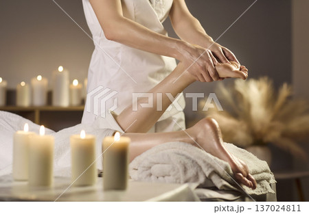 Close up foot massage therapy in spa with candles and soft towels for relaxed care 137024811