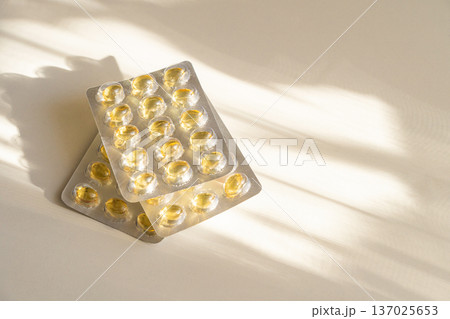 Blister pack with natural dietary supplement capsules, beige background, sunlight. Concept of daily vitamin intake, preventative medicine, wellness 137025653