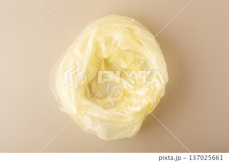 Crumpled yellow polyethylene plastic bag creating waste on a light background, symbolizing pollution and ecological concern 137025661