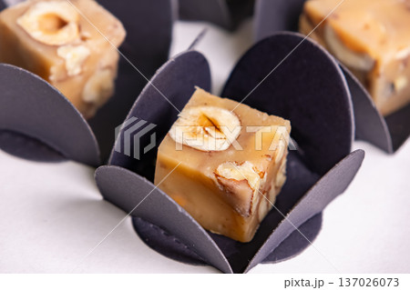 Butter caramel fudge squares with hazelnuts on white. Butter caramel fudge squares with hazelnuts on white. 137026073