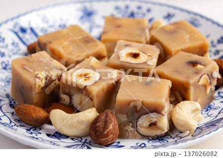 Butter fudge squares with nuts in a saucer on white table. Butter fudge squares with nuts in a saucer on white table. 137026082