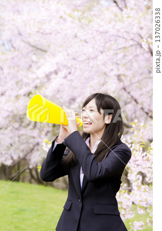桜の前でメガホンを使って声援を送るOL 137026338
