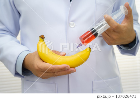 Male doctor making an injection to a banana with a syringe, penis health. Male doctor making an injection to a banana with a syringe, penis health. 137026473