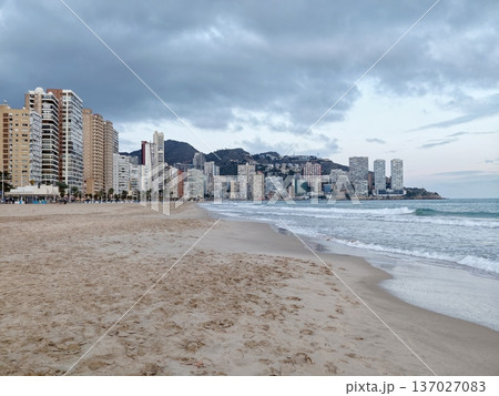 Peaceful coastal scene, Peaceful early morning by beach featuring lone person and hazy city backdrop Peaceful coastal scene, Peaceful early morning by beach featuring lone person and hazy city backdrop 137027083