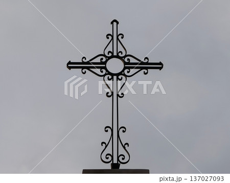 Serene portrayal of faithinspired iron craftsmanship silhouetted against cloudy sky background Serene portrayal of faithinspired iron craftsmanship silhouetted against cloudy sky background 137027093