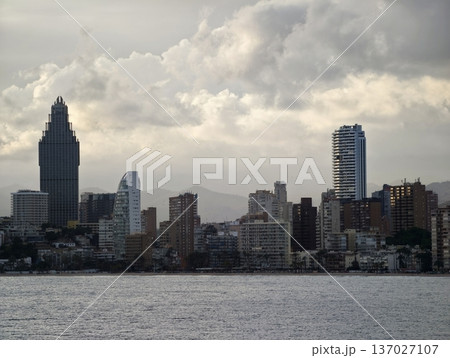 Stormy cityscape evening, Dramatic urban horizon under heavy clouds with ships and industrial cranes Stormy cityscape evening, Dramatic urban horizon under heavy clouds with ships and industrial cranes 137027107