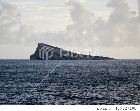 Desolate island emerging from turbulent waters, Remote rugged isle shaped by relentless ocean currents 137027109