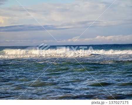Calm sea meeting cloudy sky above, Tranquil waters with ripples and distant whitecaps observed Calm sea meeting cloudy sky above, Tranquil waters with ripples and distant whitecaps observed 137027175