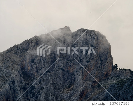 Textured limestone with moss and fissures, Misty crag reveals rugged limestone face with fissures and moss 137027193